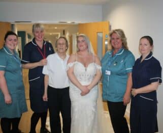 Richard Bailey with Emily Bailey in a wedding dress standing with four members of the Fair Havens Care Team