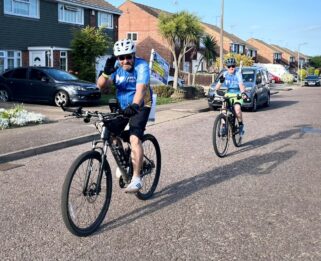 Matt Burke cycling in a the road with Finley closely followed behind on his bicycle.
