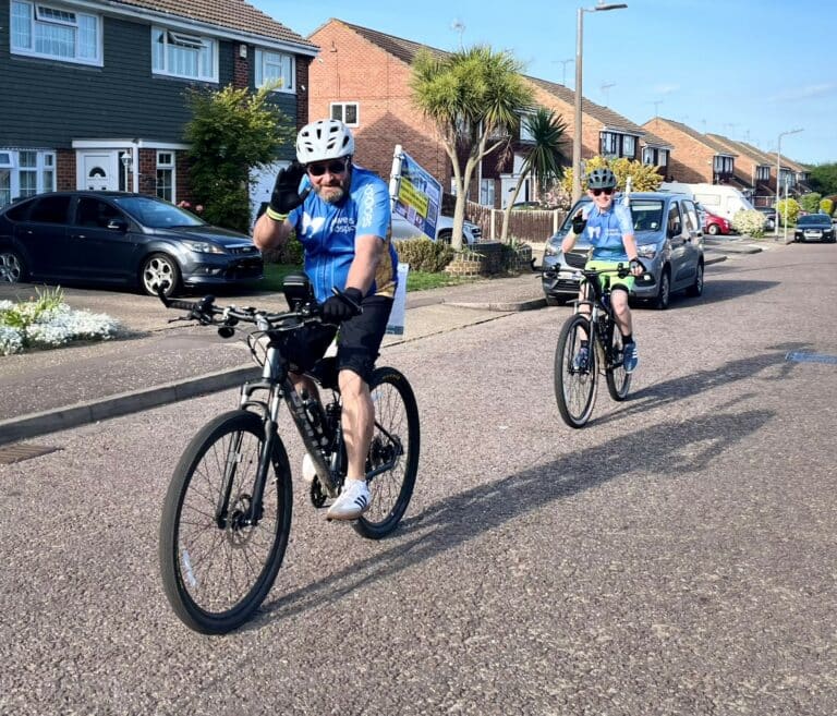 Matt Burke cycling in a the road with Finley closely followed behind on his bicycle.