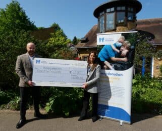 Ross Brewer and Rossella holding a large cheque outside Little Havens Hospice