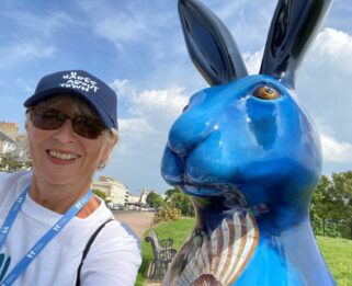 Lady standing next to large blue hare sculpture