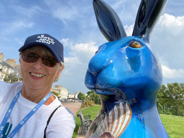 Lady standing next to large blue hare sculpture