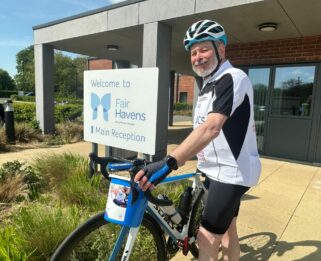 Rabbi Hyman outside Fair Havens Hospices with hid bicycle and a fundraising collection bucket