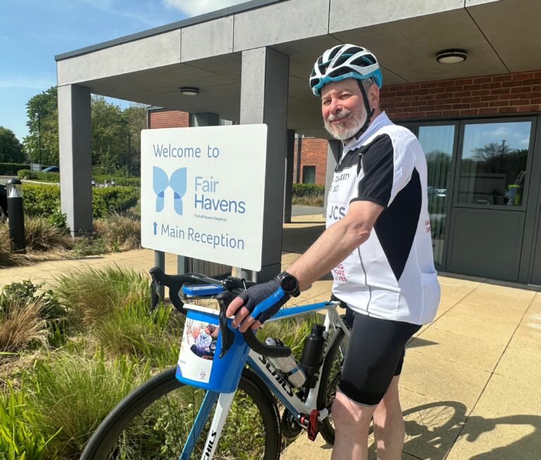 Rabbi Hyman outside Fair Havens Hospices with hid bicycle and a fundraising collection bucket