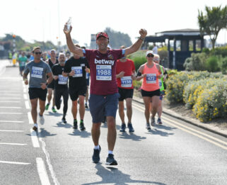 Runners on Southend seafront being lead my a male runner with his arms up in the air