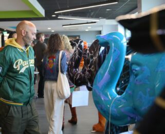 Sponsors and artists looking at decorated elephants in a row