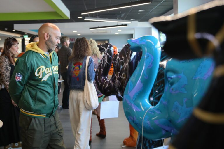 Sponsors and artists looking at decorated elephants in a row