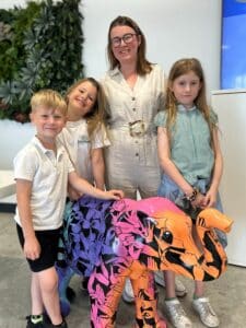 Ries Playhouse standing next to a baby elephant sculpture decorated in BSL