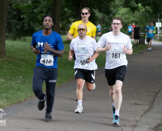 Four men running along a concrete path in Central Park Chelmsford