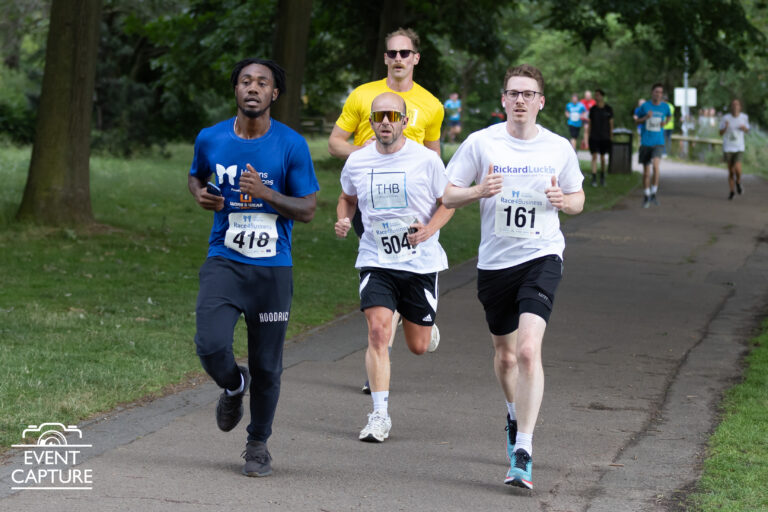 Four men running along a concrete path in Central Park Chelmsford