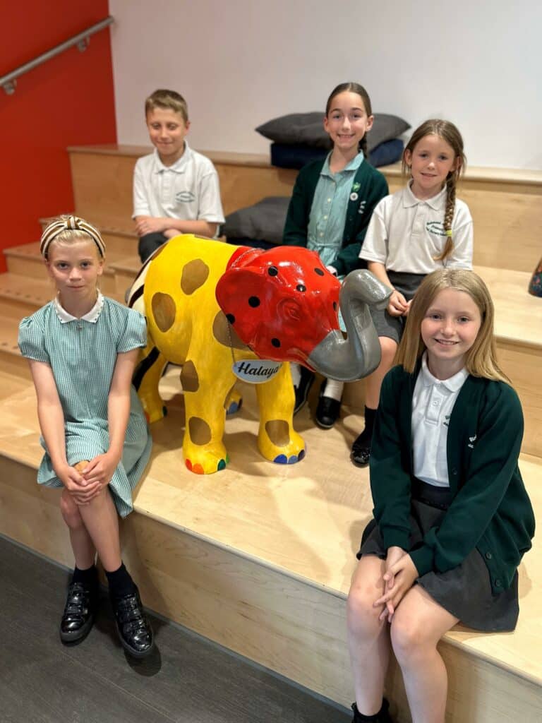 Richmond Avenue Primary School pupils sitting next to their baby elephant sculpture