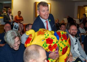 Charlie Langhorne from Wild In Art holding a baby elephant sculpture in the crowd