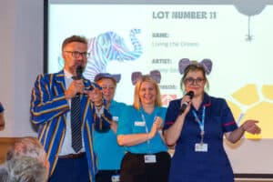 Charles Hanson with three nurses from Havens Hospices on stage encouraging bids from the audience