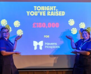 Two nurses from Havens Hospices presenting the total raised on the night of the auction, £180,000, on a screen