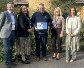 Two representatives from charity Havens Hospices and three representatives from DP World standing outside Little Havens holding a framed certificate