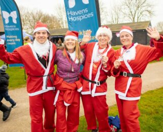 Four people dressed in Santa outfits at the Havens Hospices Run Santa Run event in 2022