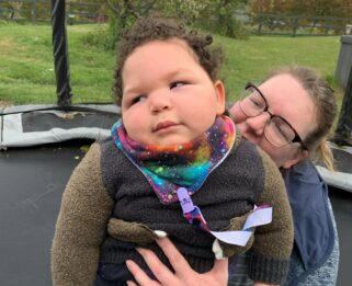 A mother holding her son on a trampoline at Little Havens