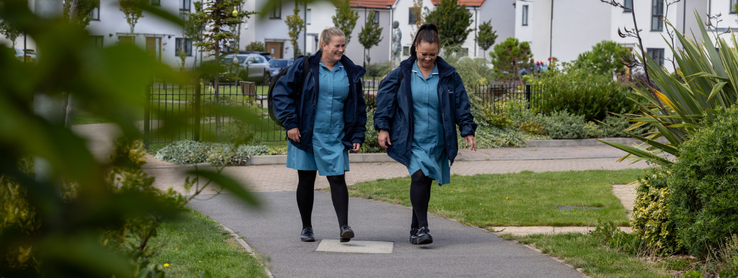 Two community nurse assistants waking down a pat in a housing estate