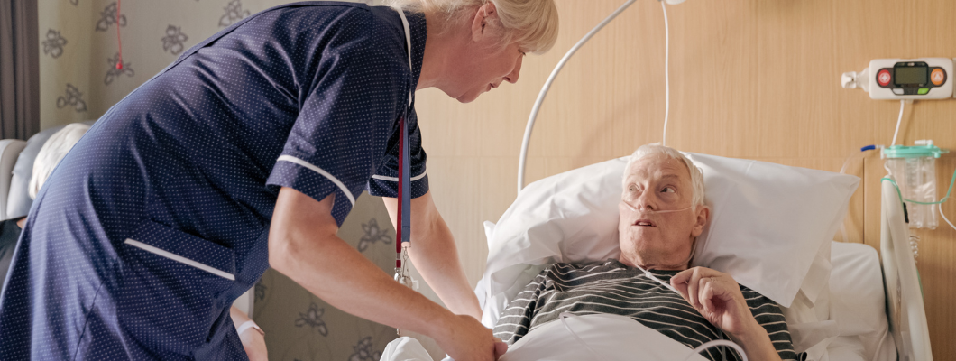 Patient in bed talking to nurse.