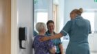 A nurse puts her hand on the back of a patient.