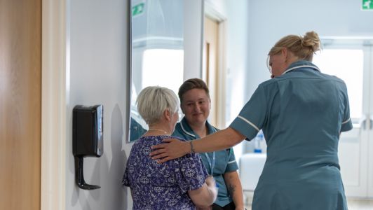 A nurse puts her hand on the back of a patient.