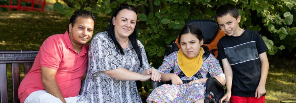 A family sat outside together in the garden all smiling at the camera