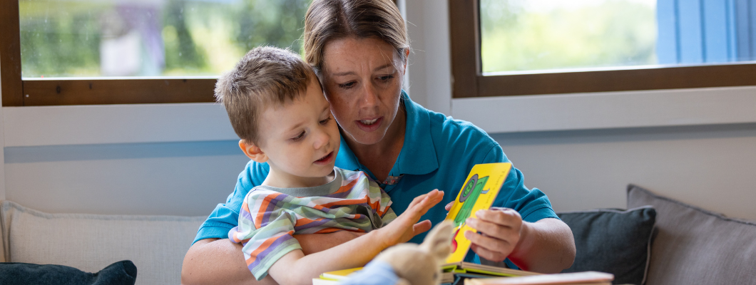 Little boy reading a book with a nurse at Little Havens