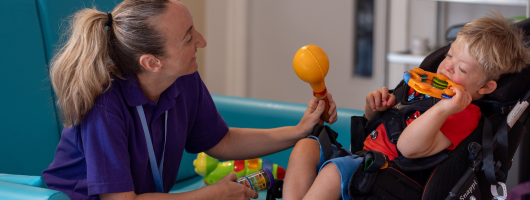 Little boy with health care assistant playing with music at Little Havens