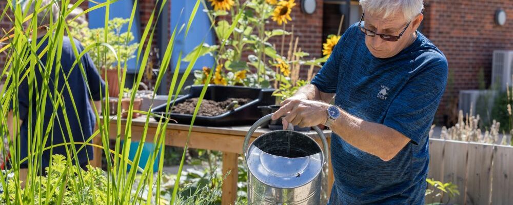 Trevor in the Fair Havens graden, watering the plants.