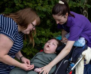 Elijah outside with mum and healthcare assistant, Emma.