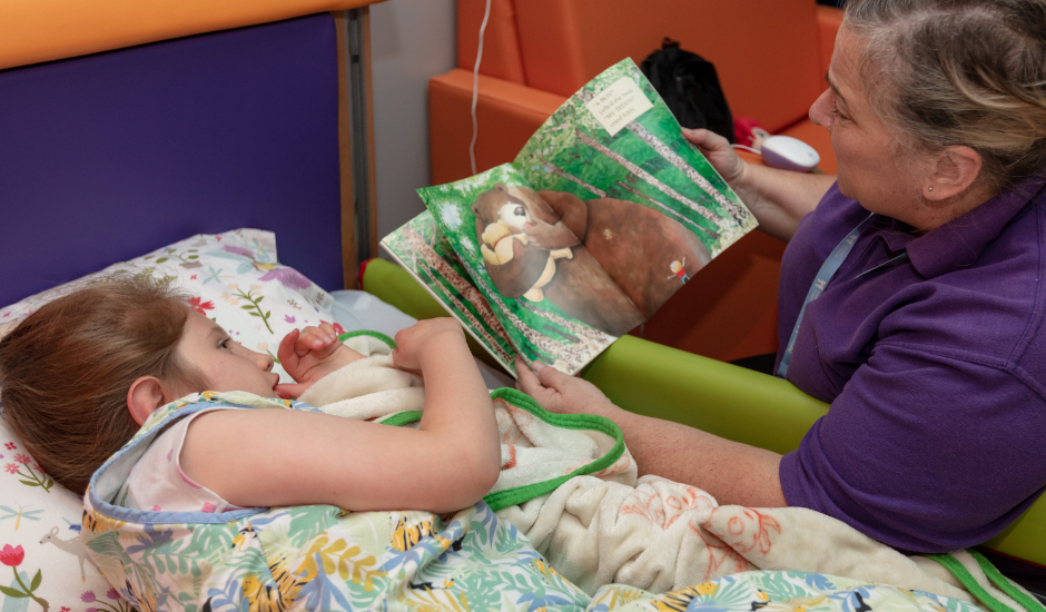 Child having a story read to her in bed