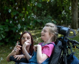 Alex and her mum playing with bubbles in Little Havens garden