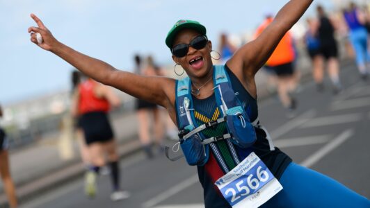 Lady smiling with hands in the air jumping as she runs