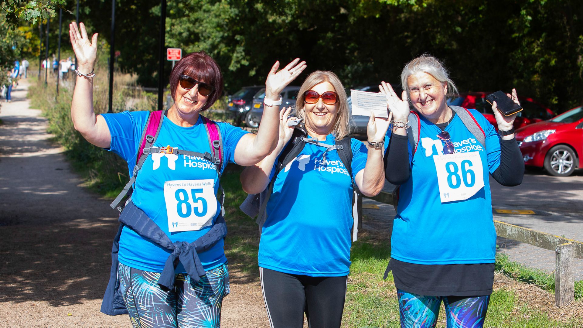 Three Havens Hospices supporters taking part in a sponsored walk, wave to the camera