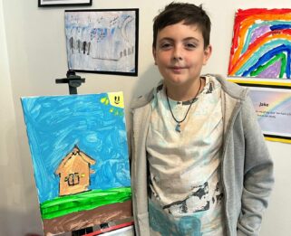 Oliver at the Leigh Art Trail stood next to his painting.