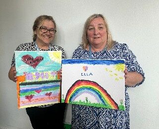 Jane and Tracy holding art work.