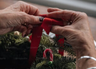 A close up of hands creating a christmas wreath