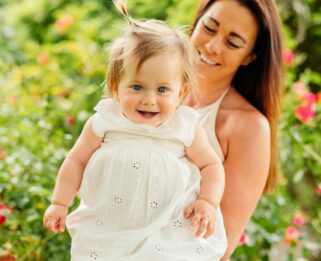 Sarah holding Allani with flowered gardens in the background