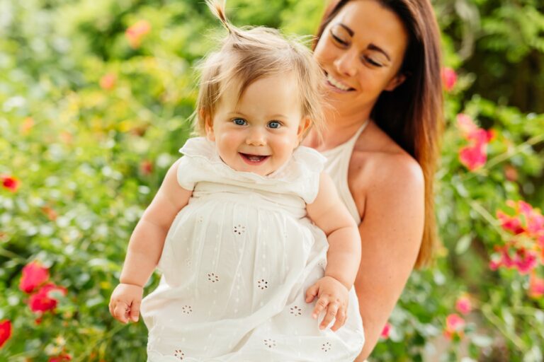 Sarah holding Allani with flowered gardens in the background