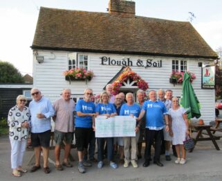 Group of people stand outside the Plough and Sail Pub with a cheque for Havens Hospices
