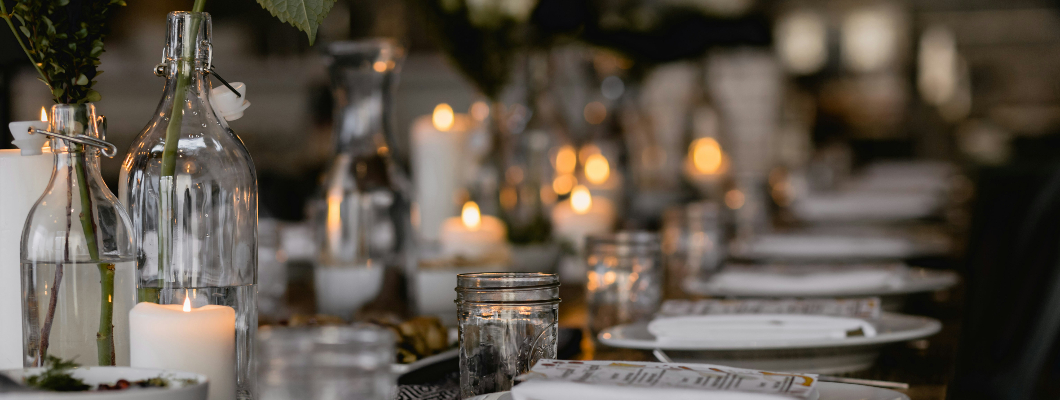 A dinner setting, with candles placed along the centre of the table
