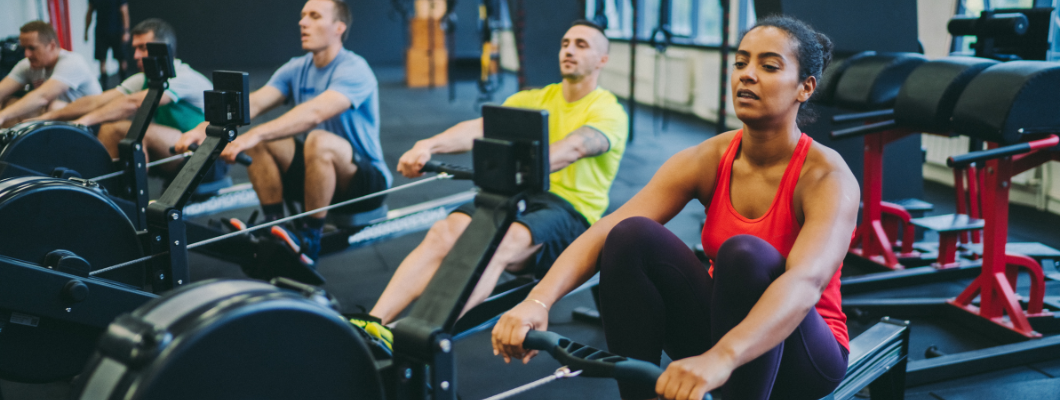 People on rowing machine in gym.