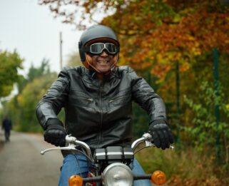 Man riding a motorcycle in the centre of the image surrounded by road and greenery
