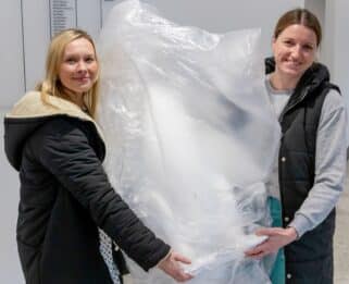 Two people holding wrapped up baby penguin
