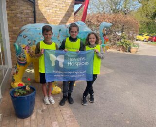 Joe, Fin and Jack at Little Havens holding a Havens Hospices banner.