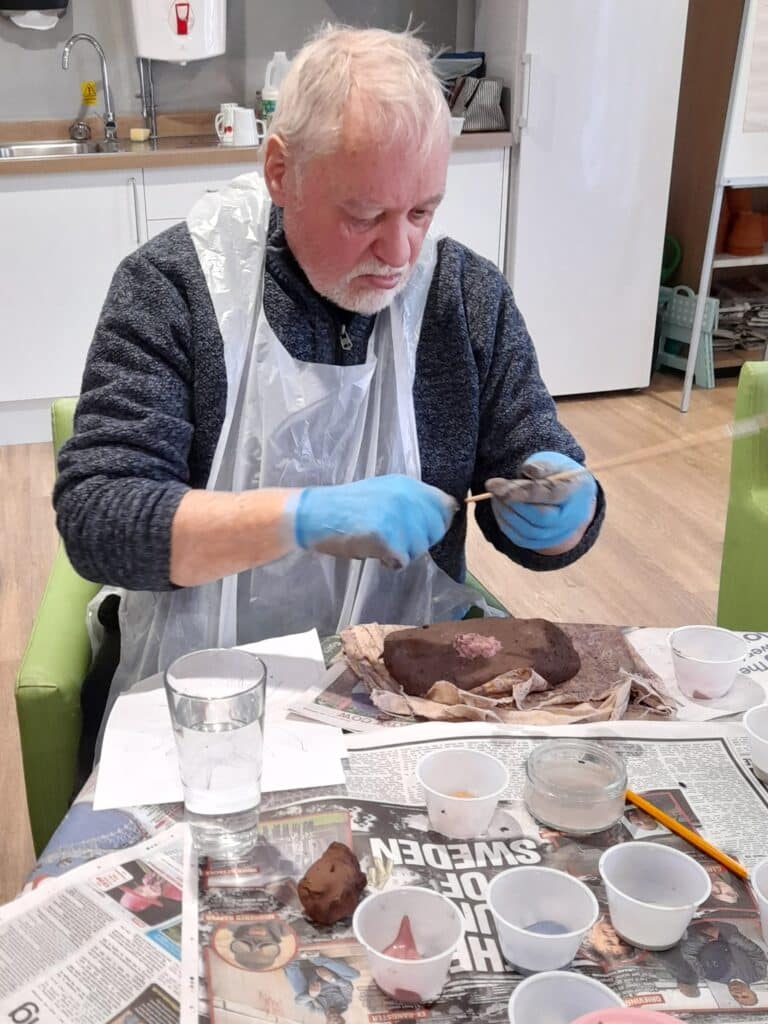 Fair Havens patient Bryan painting a seed.