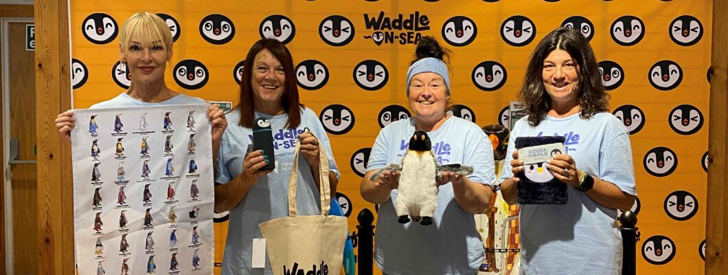 Volunteers holding some of the penguin merchandise available.