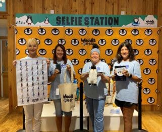 Volunteers holding some of the penguin merchandise available.