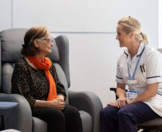 A lady sitting taking to a physiotherapist at Fair Havens.