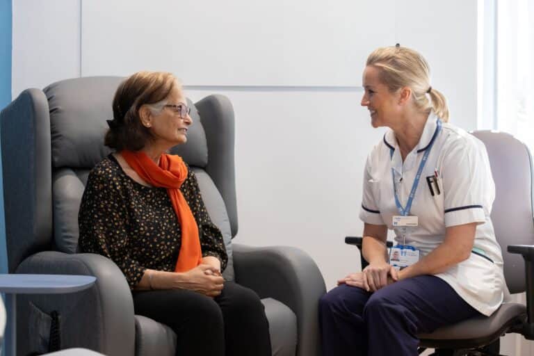 A lady sitting taking to a physiotherapist at Fair Havens.